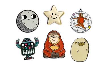 A collection of 6 super cute pins: a small moon, a gold smiley star, a dancing sloth, a party robot, a talking orangutan, and a pugtato.