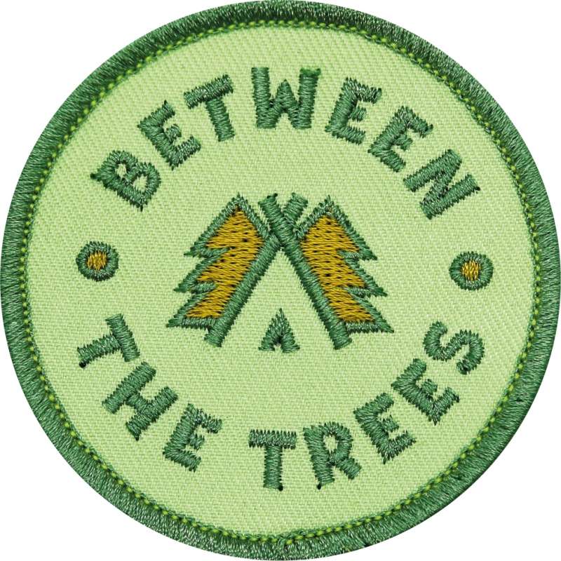An embroidered green patch for the Between The Trees festival.