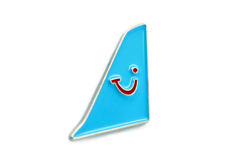 A blue pin badge of an aeroplane tail fin that features the TUI logo.