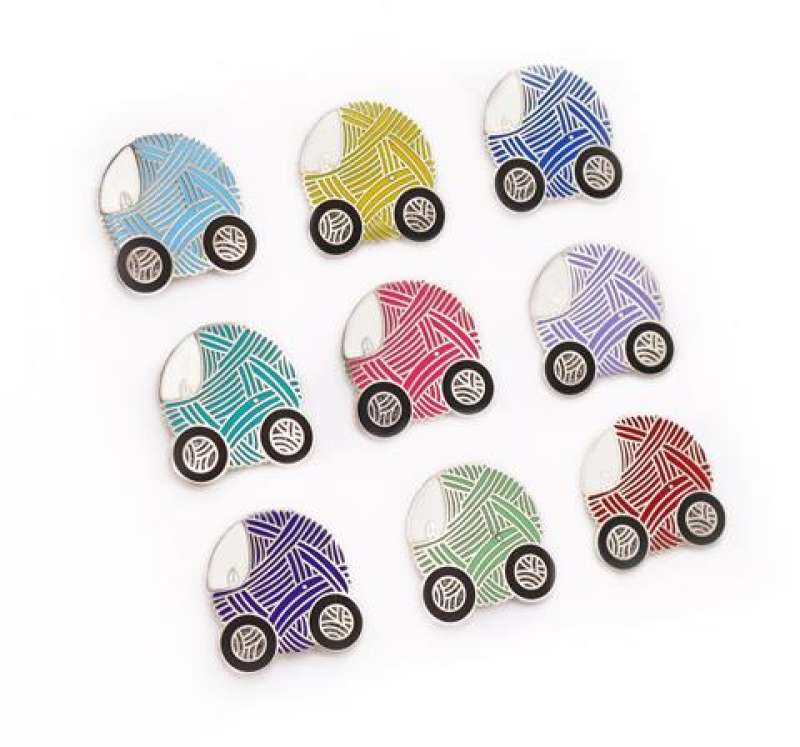 Nine hard enamel pin badges featuring the same design of a little car made from a ball of wool. Each car is a different colour. Light blue, yellow, royal blue, teal, red, violet, pink, purple, and green.