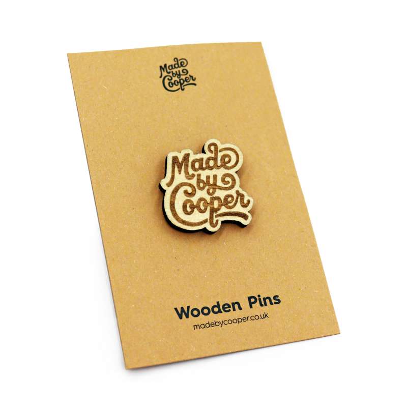 A wooden Made by Cooper pin badge on a brown craft backing card.