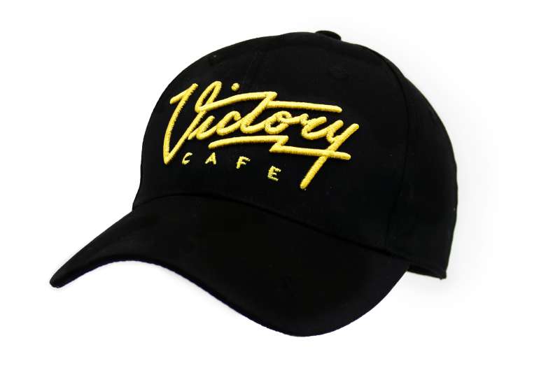 A black baseball cap with Victory Cafe embroidered in yellow.
