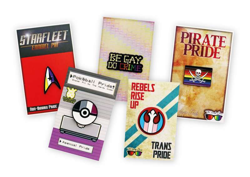 A collection of LGBTQ+ activism enamel pin badges and backing cards.