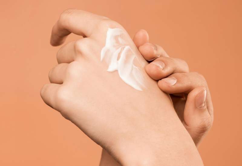 Someone applying lotion to skin on hands.