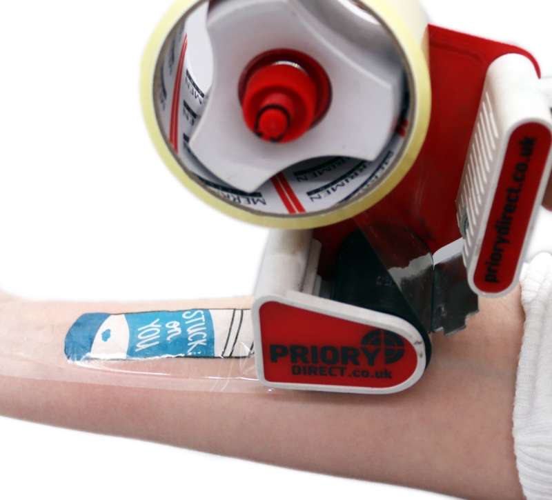 A tape dispenser applying tape over a temporary tattoo on an arm.