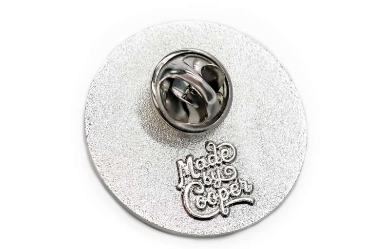 The rear of a silver plated enamel pin badge that displays the Made by Cooper logo to make each unit less expensive.