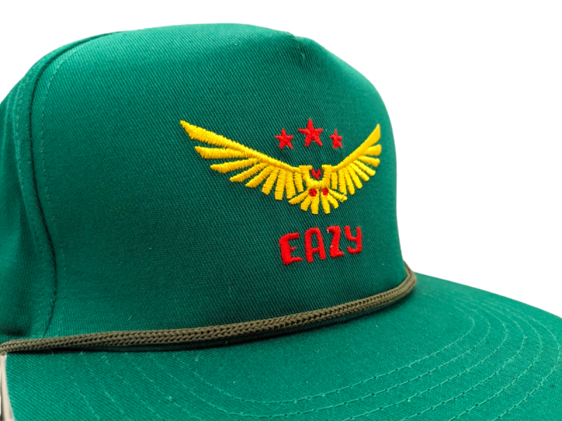 A green baseball cap with a winged design with stars embroidered on the front.