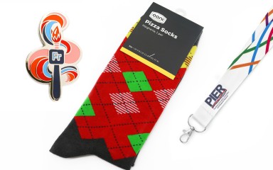 A set of branded merch. A custom pin badge, branded socks, and corporate lanyard.