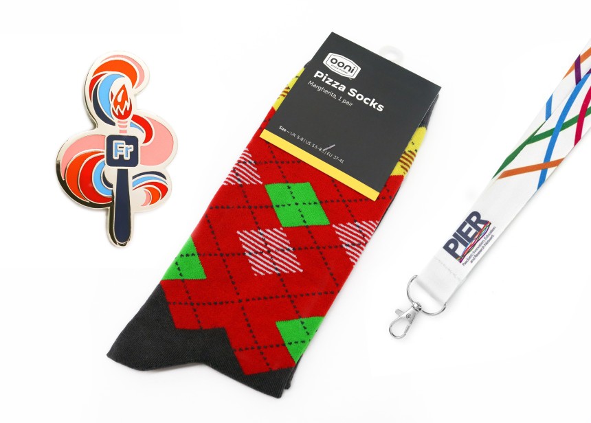 A set of branded merch. A custom pin badge, branded socks, and corporate lanyard.