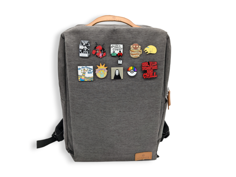 A backpack with ten enamel pin badges attached to it ready to fly on a plane.