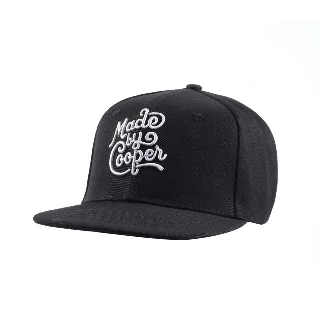 A black custom baseball cap, with a flat peak and snapback. The custom hat has the Made by Cooper logo embroidered on the front.