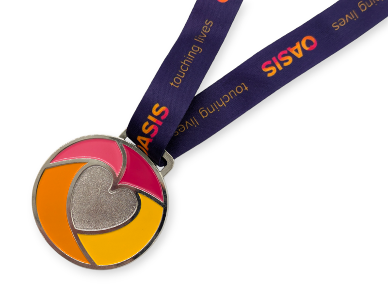 A charity race medal that features a heart logo in the middle of a multi-coloured pattern. The words 