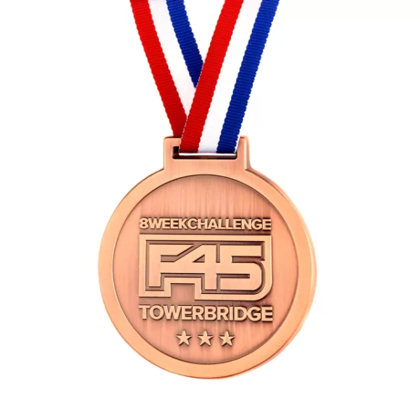 A copper coloured custom medal for the F45 Towerbridge Challenge. Attached to the medal is a red, white, and blue striped ribbon.