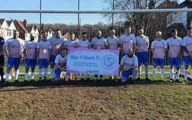 A football team photo crowded around a fund-raising banner under the goal posts.