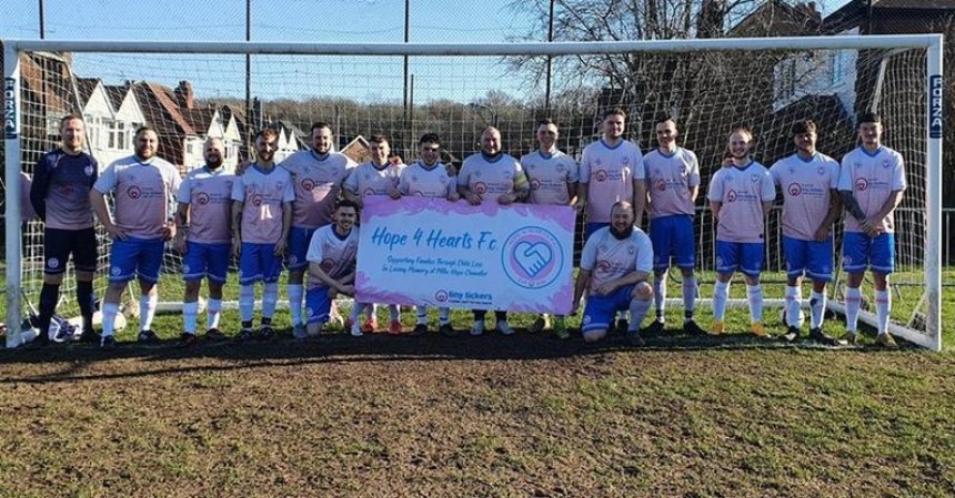 A football team photo crowded around a fund-raising banner under the goal posts.