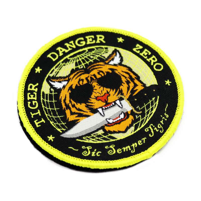 A custom velcro patch featuring a tiger wearing sunglasses holding a dagger between its teeth. 