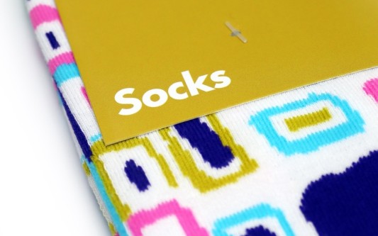 A close up of some brightly coloured socks with a branding card that simply says 