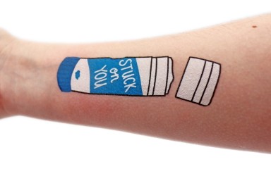 An arm that has a temporary tattoo of a glue stick that says 