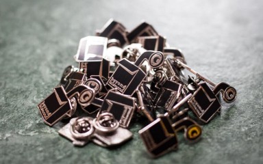 A pile of black and gold pin badges.