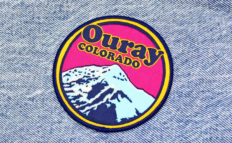 A colourful Ouray Colorado iron-on patch stuck to a piece of denim.