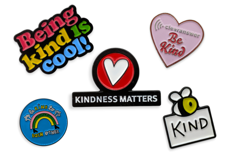 Five enamel pins with variations of the phrase 'be kind' to promote better mental health.