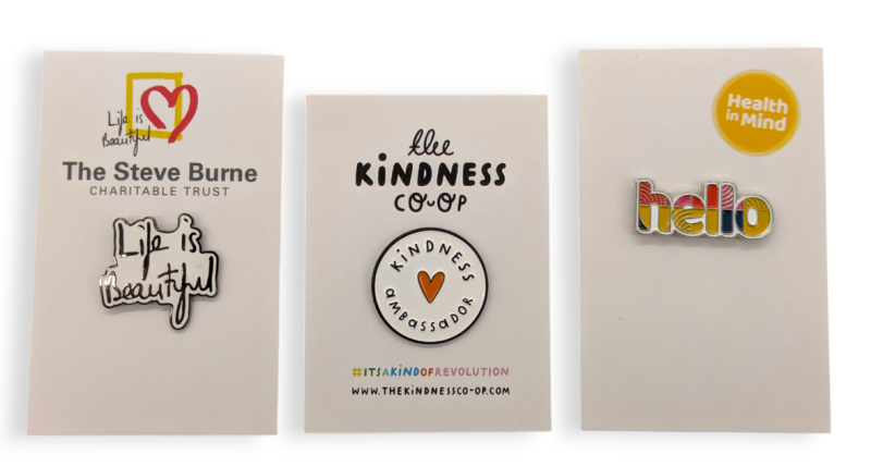 Three pin badges attached to backing cards that promote better mental health and help raise money for charity.