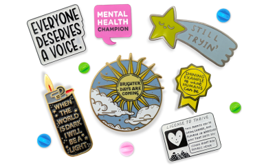 A collection of enamel pins with designs that promote mental health positivity.