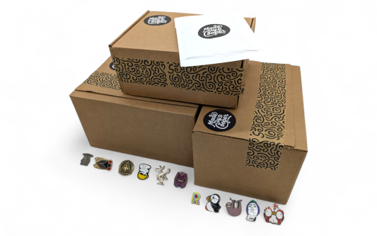 A pile of Made by Cooper branded boxes and envelopes surrounded by pin badges to show people how and why packaging for pin badges is essential.