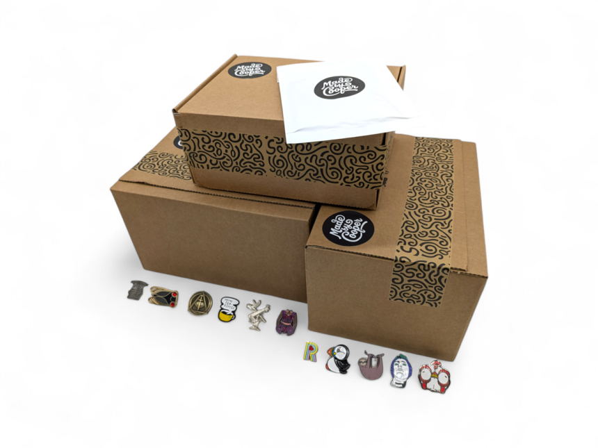 A pile of Made by Cooper branded boxes and envelopes surrounded by pin badges to show people how and why packaging for pin badges is essential.