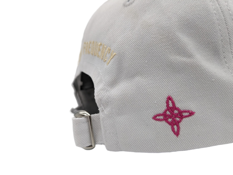 A white cap with pink and gold logos embroidered onto the rear.