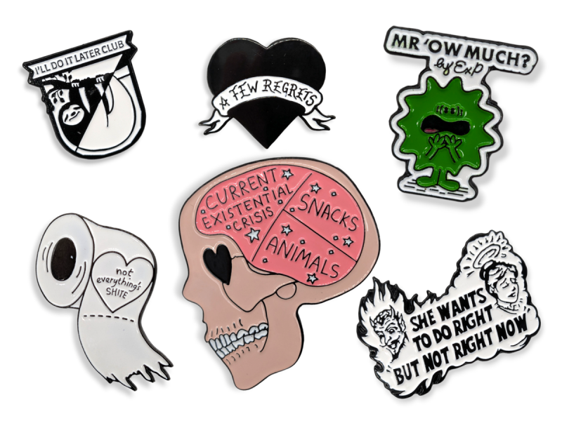 A collection of enamel pins poking fun at the wearing with phrases like 'A few regrets' 'Mr Ow Much?' and 'Not everything is shite'.