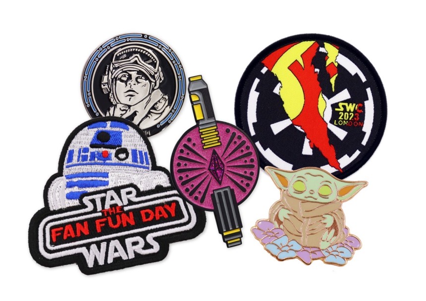 A collection of Star Wars pins and patches featuring Master Yoda, Luke Skywalker, R2D2, and Lightsabers.