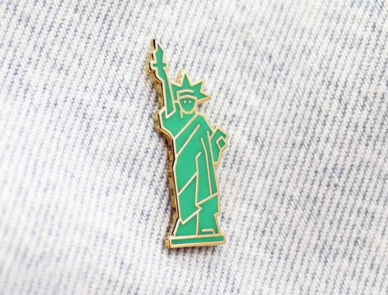 A statue of liberty pin badge pinned to some stonewash denim.