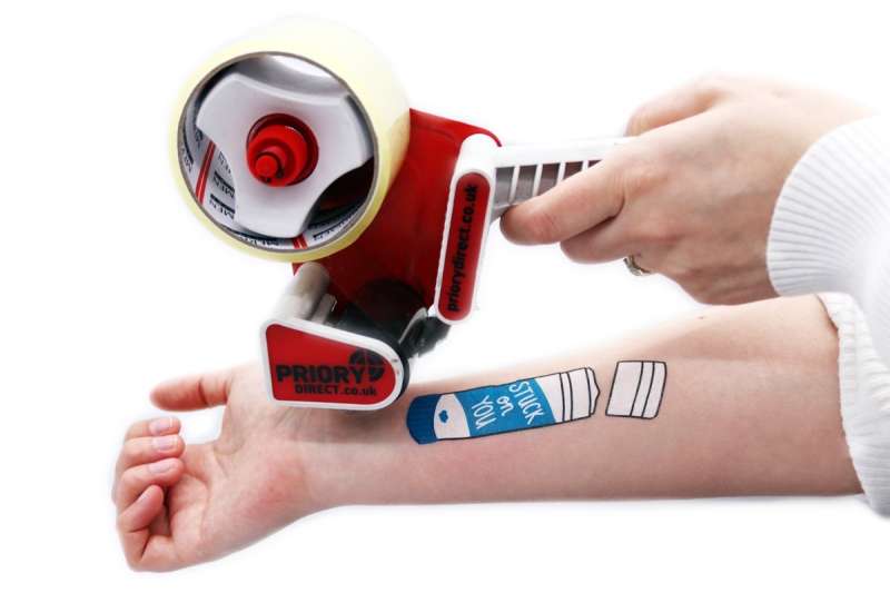 An arm with a temporary tattoo and a tape dispenser ready to apply some selotape.