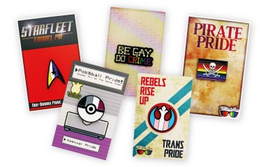 A collections of five lapel pins on backing cards featuring designs from our client The Nerdy Queer. Star trek pride pins, Star Wars LGBTQ+ badges, and Pokemon enamel products.