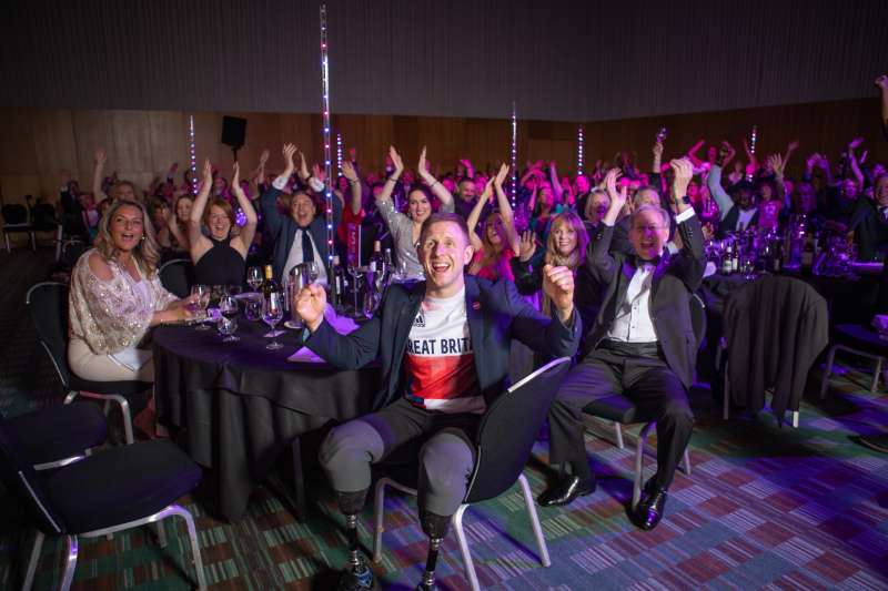 A room full of people at the awards ceremony applaud and cheers the winners.