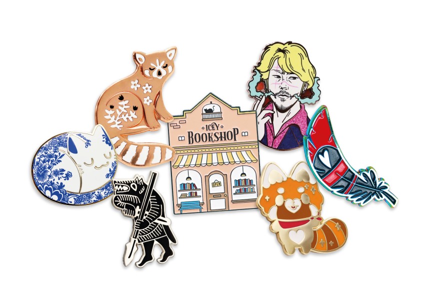 A collection of expensive looking pin badges including a sleeping cat, large book shop, a fox, a blue and red feather, a spear weilding wolf, and a dude smoking a cigarette. He looks shifty.