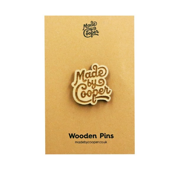 A brown backing card holds a wooden pin badge in the shape of the Made by Cooper logo.